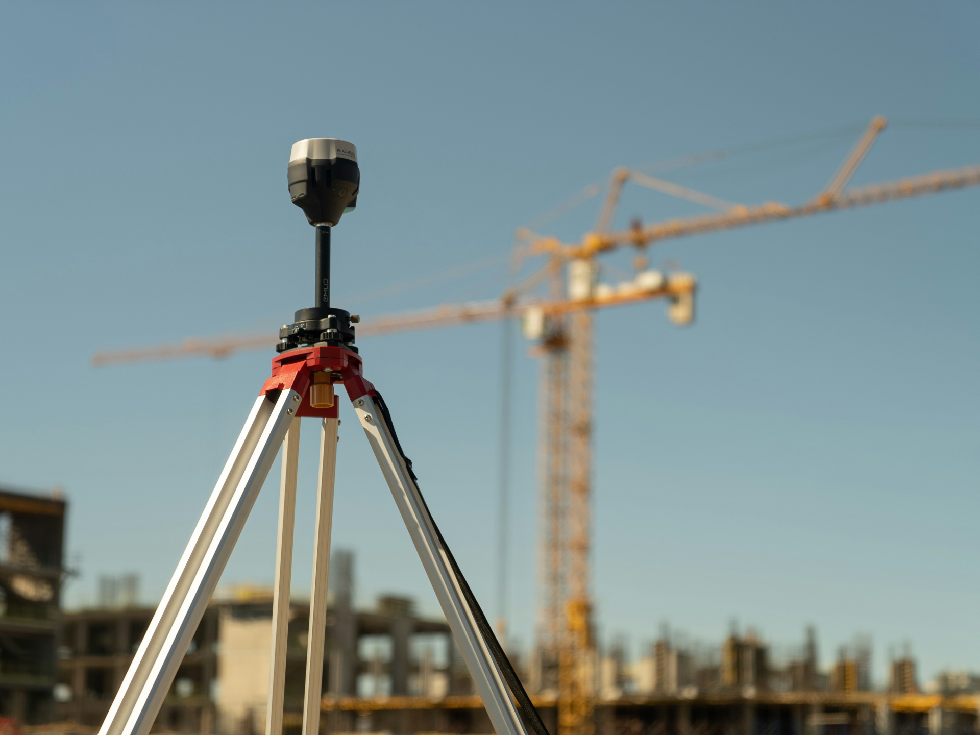 Surveying equipment on a construction site with a tower crane in the background